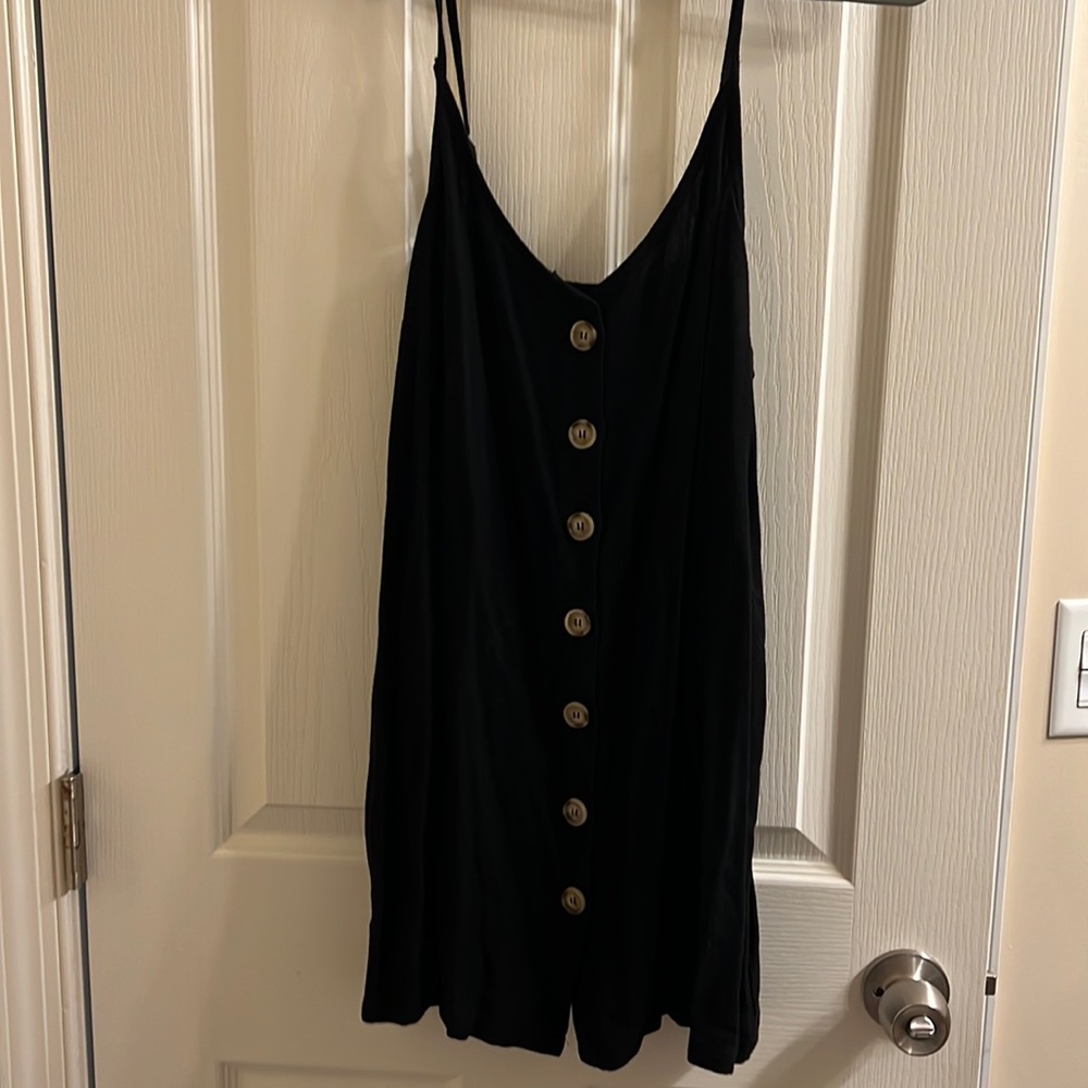 Black mini dress with adjustable straps. Buttons in the front. Pink Lily.